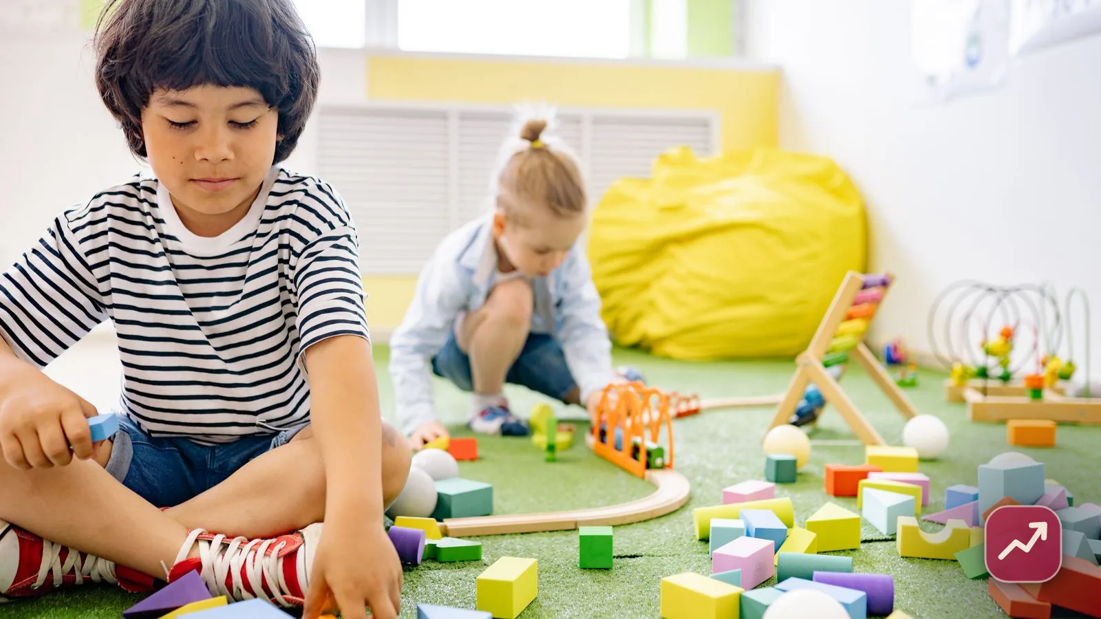 Young children playing with colourful blocks at a bright daycare, illustrating childcare costs.